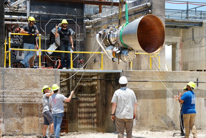 Engineers installing a rocket engine at a test facility, showcasing teamwork and precision in aerospace engineering.